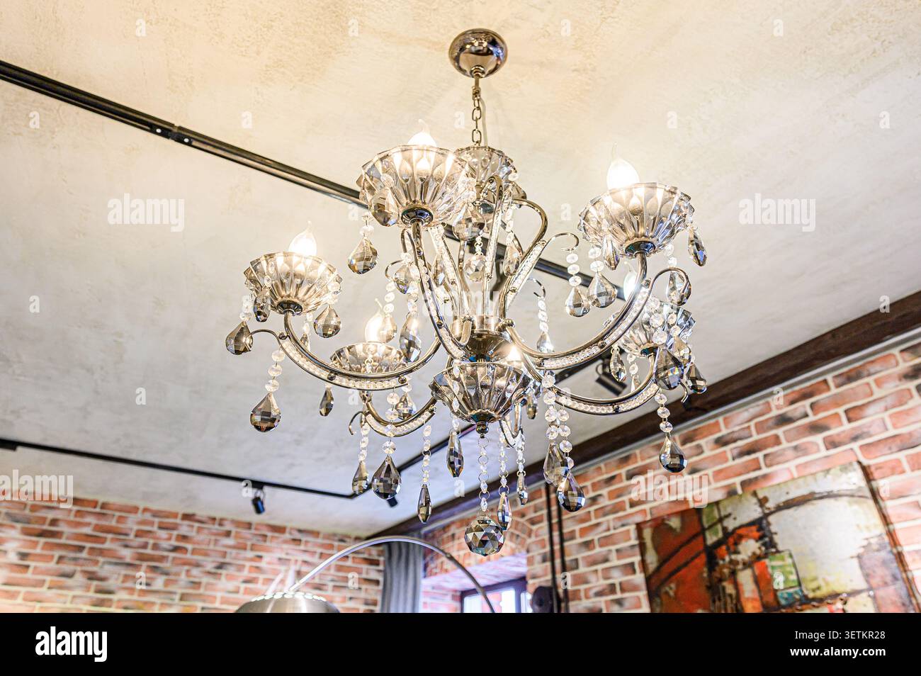 Elegante lampadario con pendenti in cristallo appeso al soffitto. È dotato di più sorgenti luminose e dettagli intricati Foto Stock
