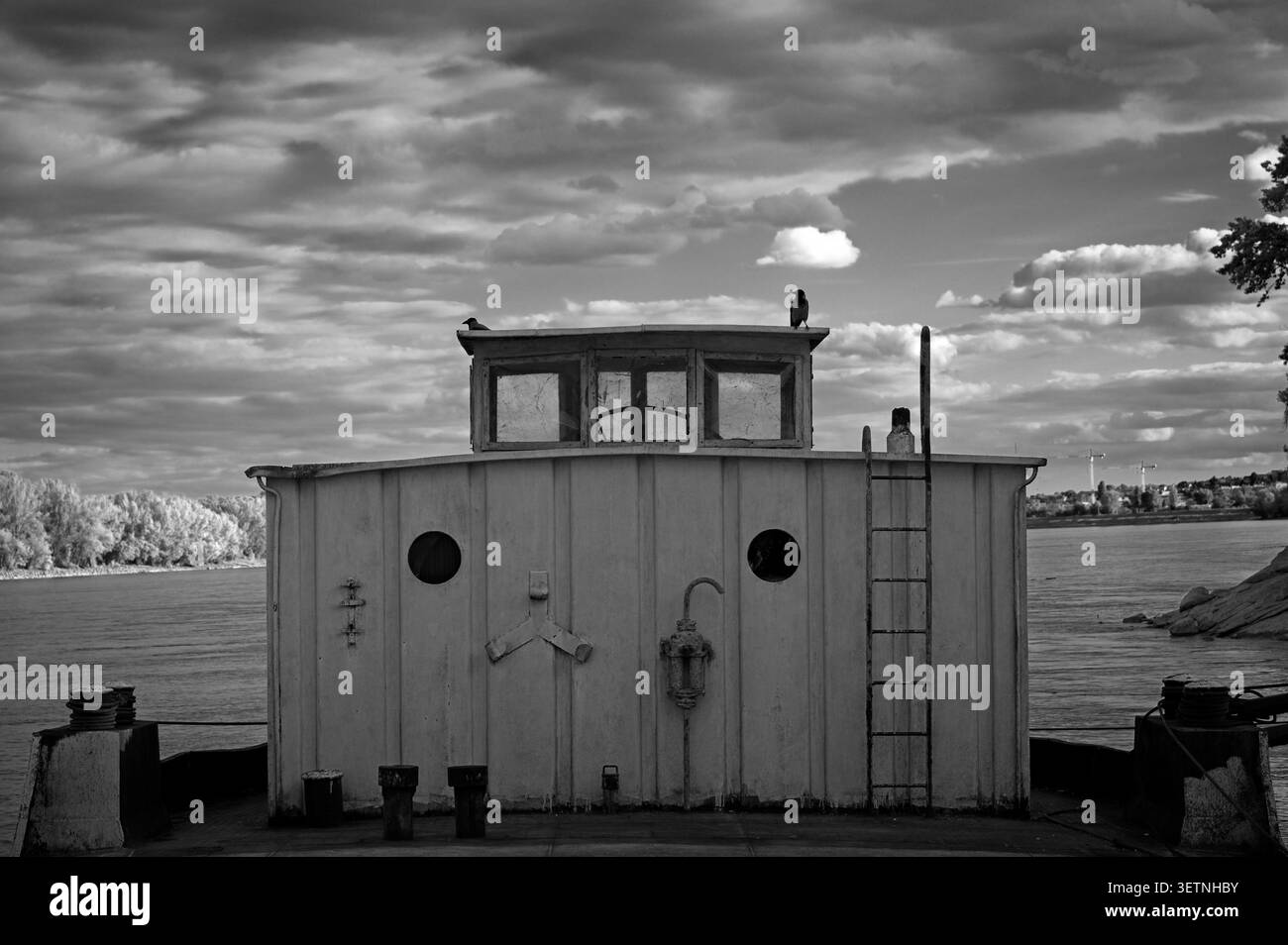 Budapest, Ungheria - 12 giugno 2026: Foto in bianco e nero di una vecchia cabina di metallo sul Danubio a Kopaszi-Gat, con corvi sotto un cielo nuvoloso. Foto Stock