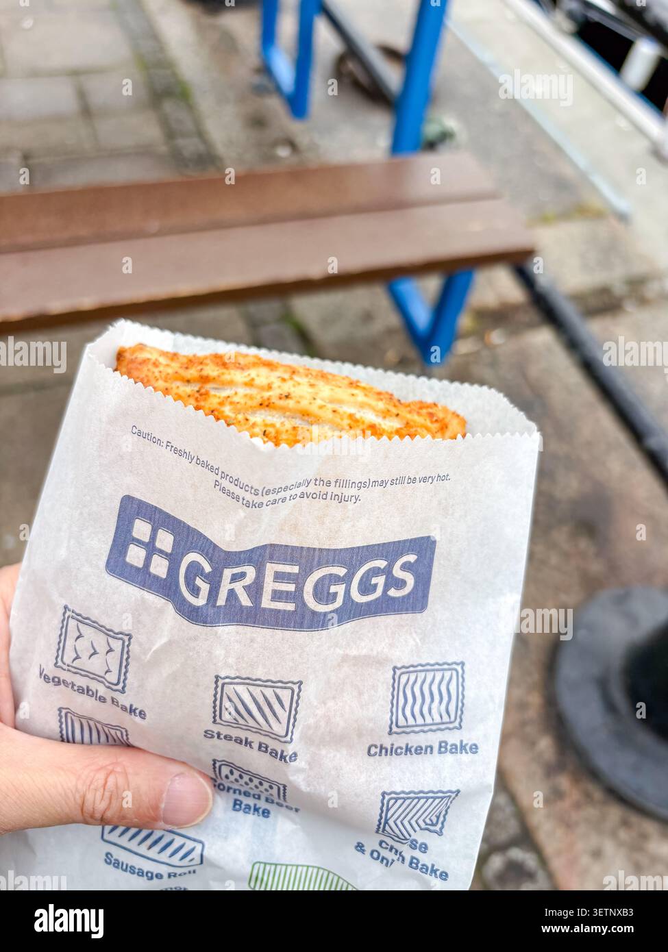 Un dolce salato appena sfornato contenuto in un sacchetto di carta firmato Greggs. Foto Stock