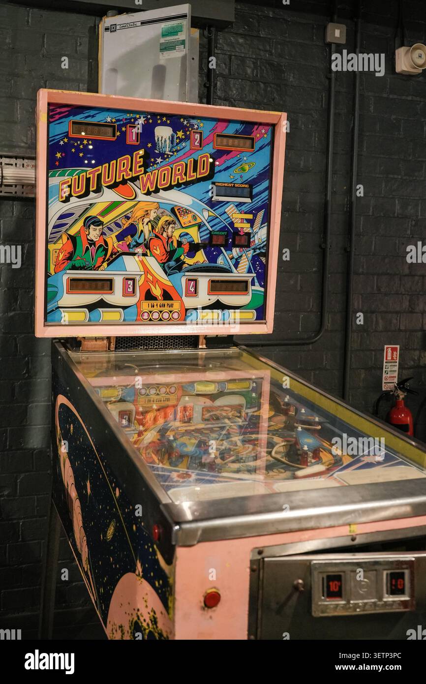 Una flipper vintage Future World si trova di fronte a una parete di mattoni scuri dipinti. Foto Stock