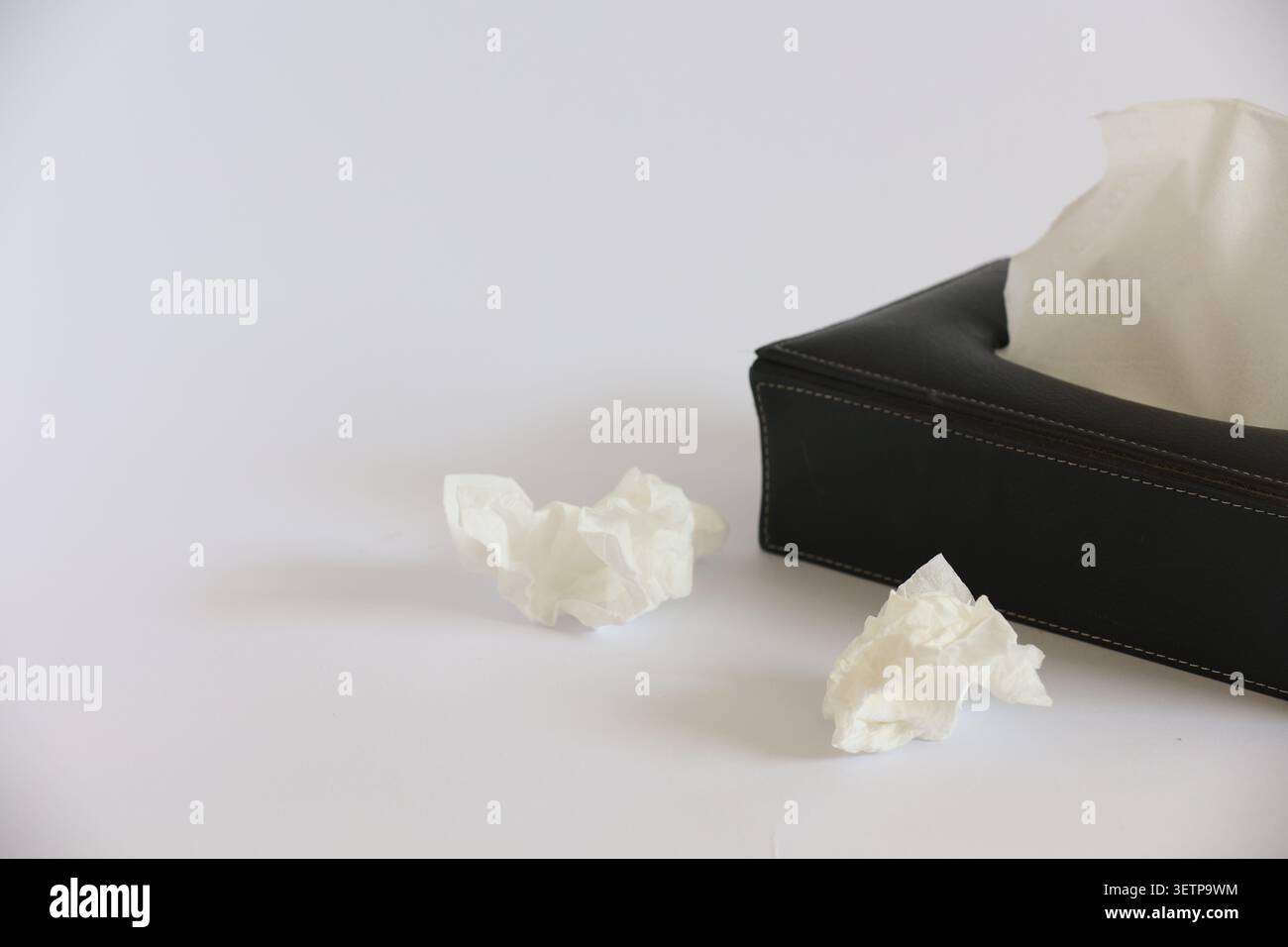 Scatola di tessuto nera con tessuto tirato e carta bianca sgualcita Foto Stock