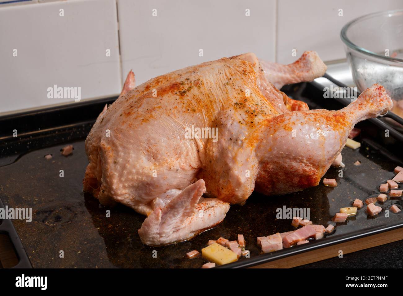Pollo crudo condito su un vassoio da forno in metallo con pancetta a dadini e formaggio per la tostatura Foto Stock