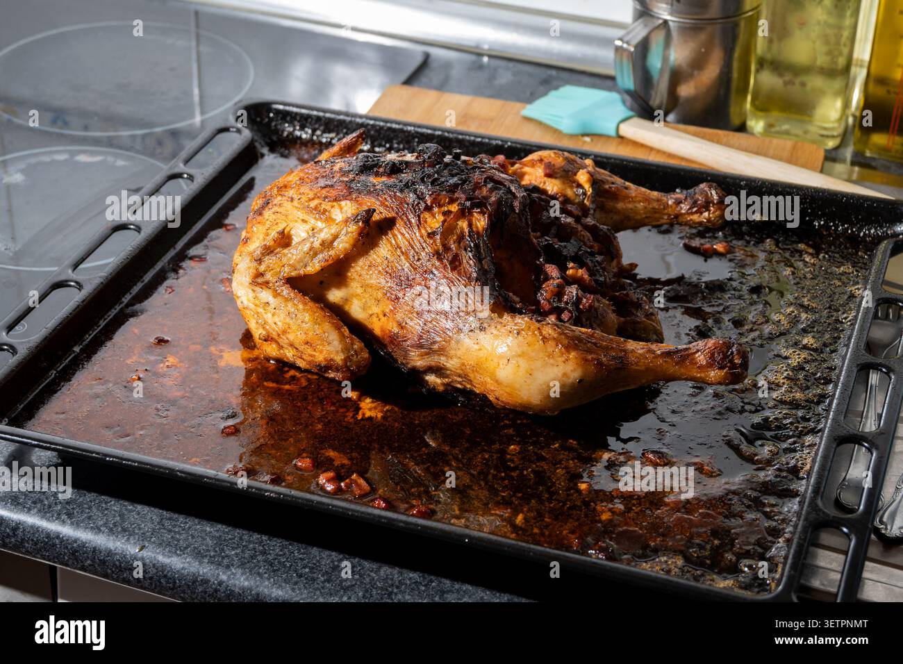 Pollo arrosto su una teglia da forno sporca con grasso e pezzi bruciati dopo la cottura Foto Stock
