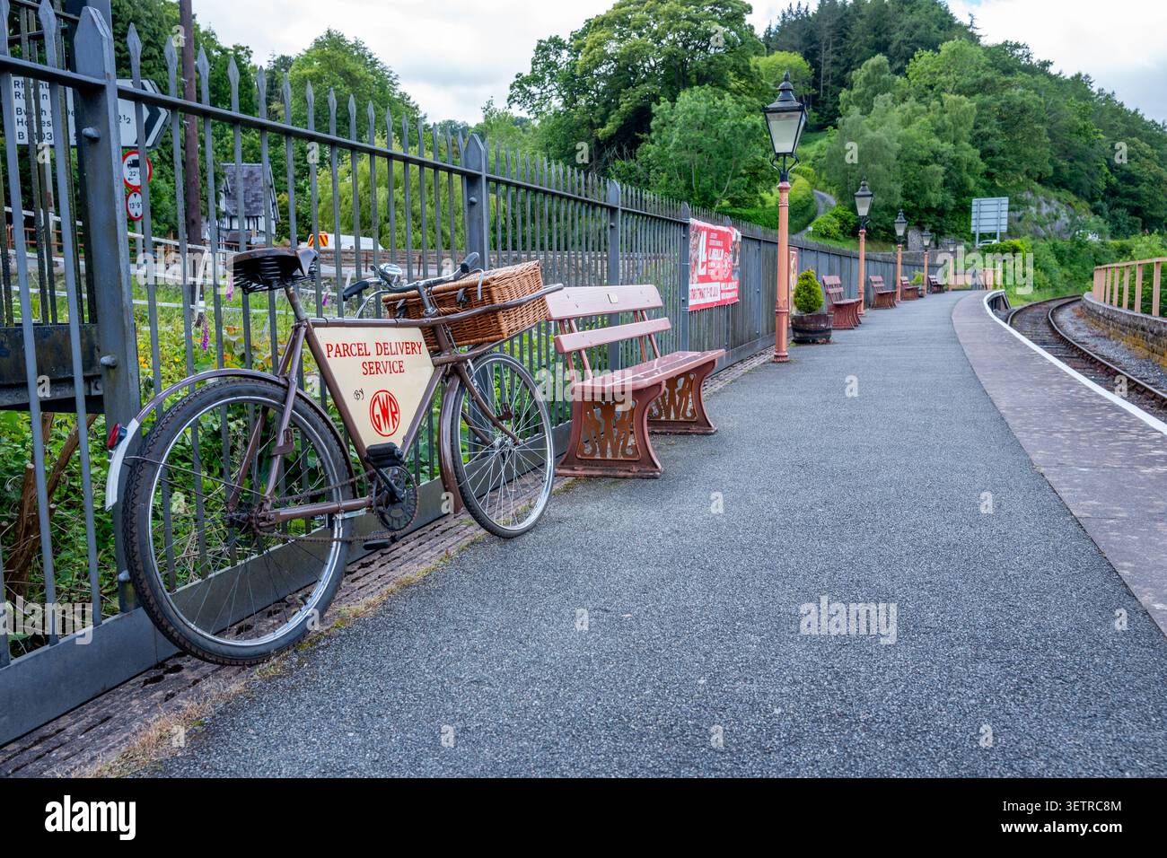 Servizio di consegna pacchi utilizzando una bicicletta con cesto utilizzato come sostegno sul binario della stazione ferroviaria di Berwyn sulla ferrovia di Llangollen. Foto Stock