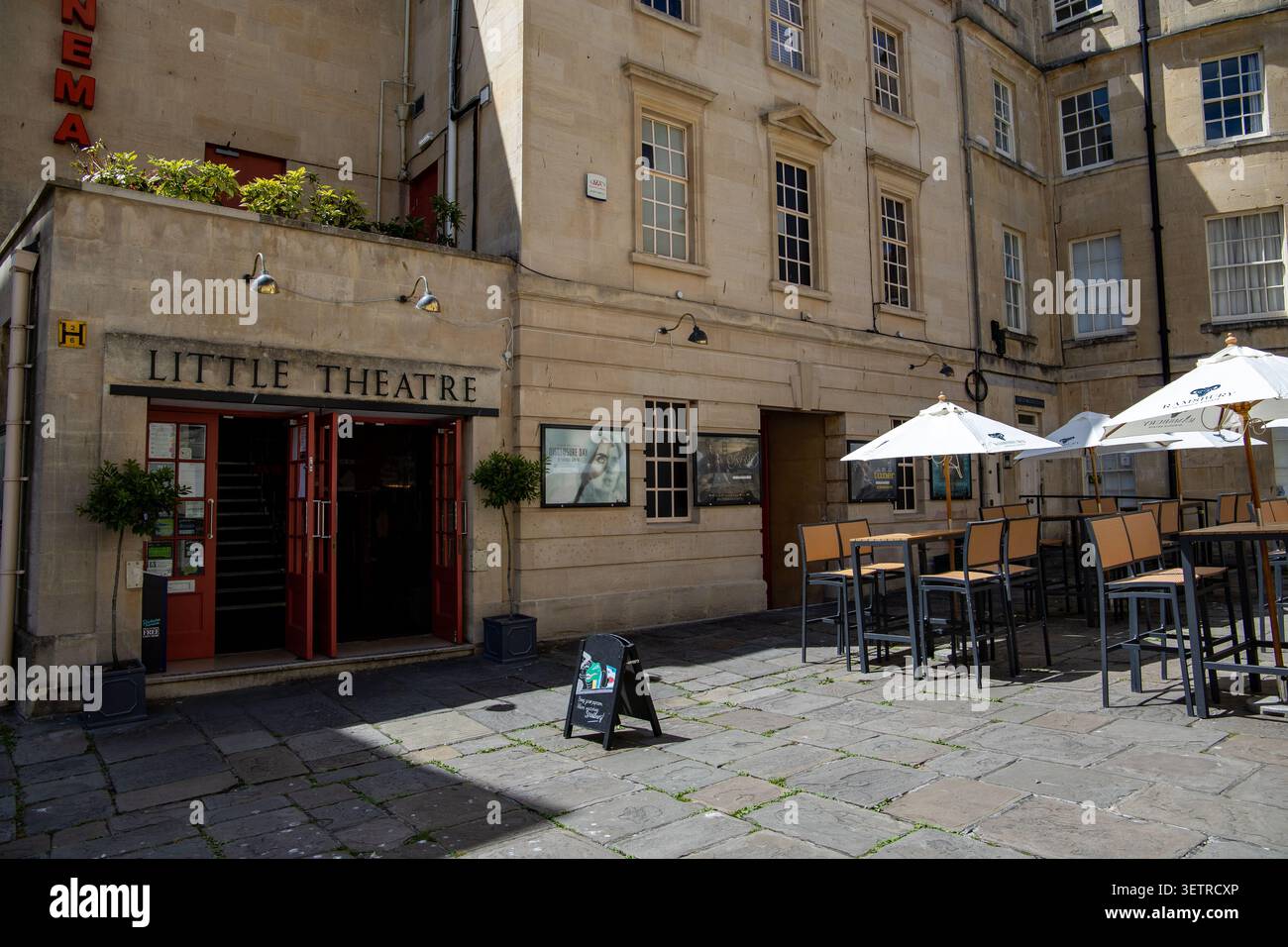 Ingresso al Little Theatre di Bath, Regno Unito, in uno storico edificio in pietra calcarea con un'area salotto all'aperto con tavoli e ombrelloni bianchi Foto Stock