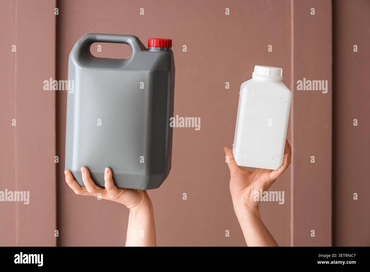 Mani che tengono in mano grandi contenitori di plastica grigi e bianchi Foto Stock
