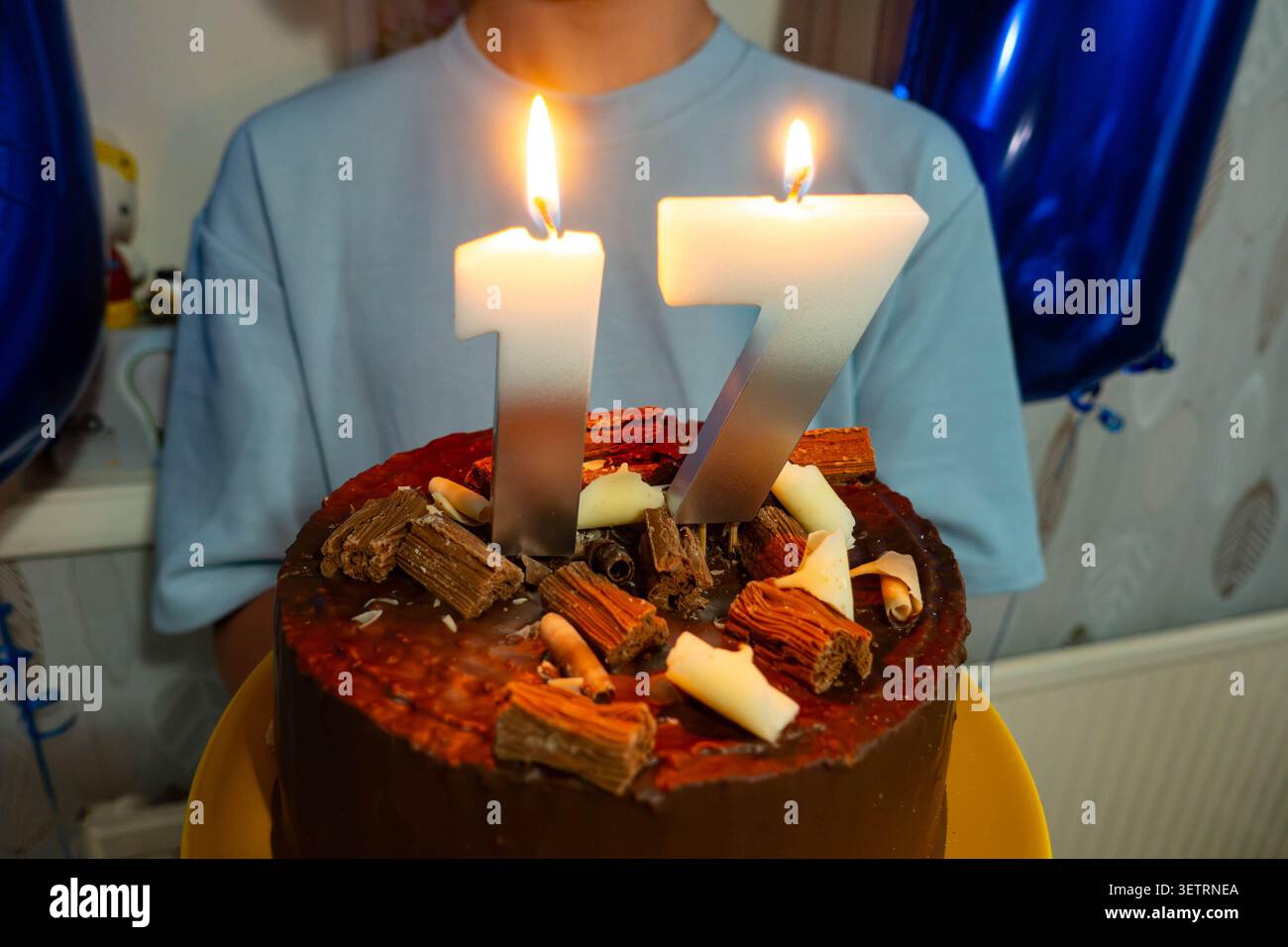 Un adolescente che tiene la sua torta di compleanno per il suo diciassettesimo compleanno Foto Stock