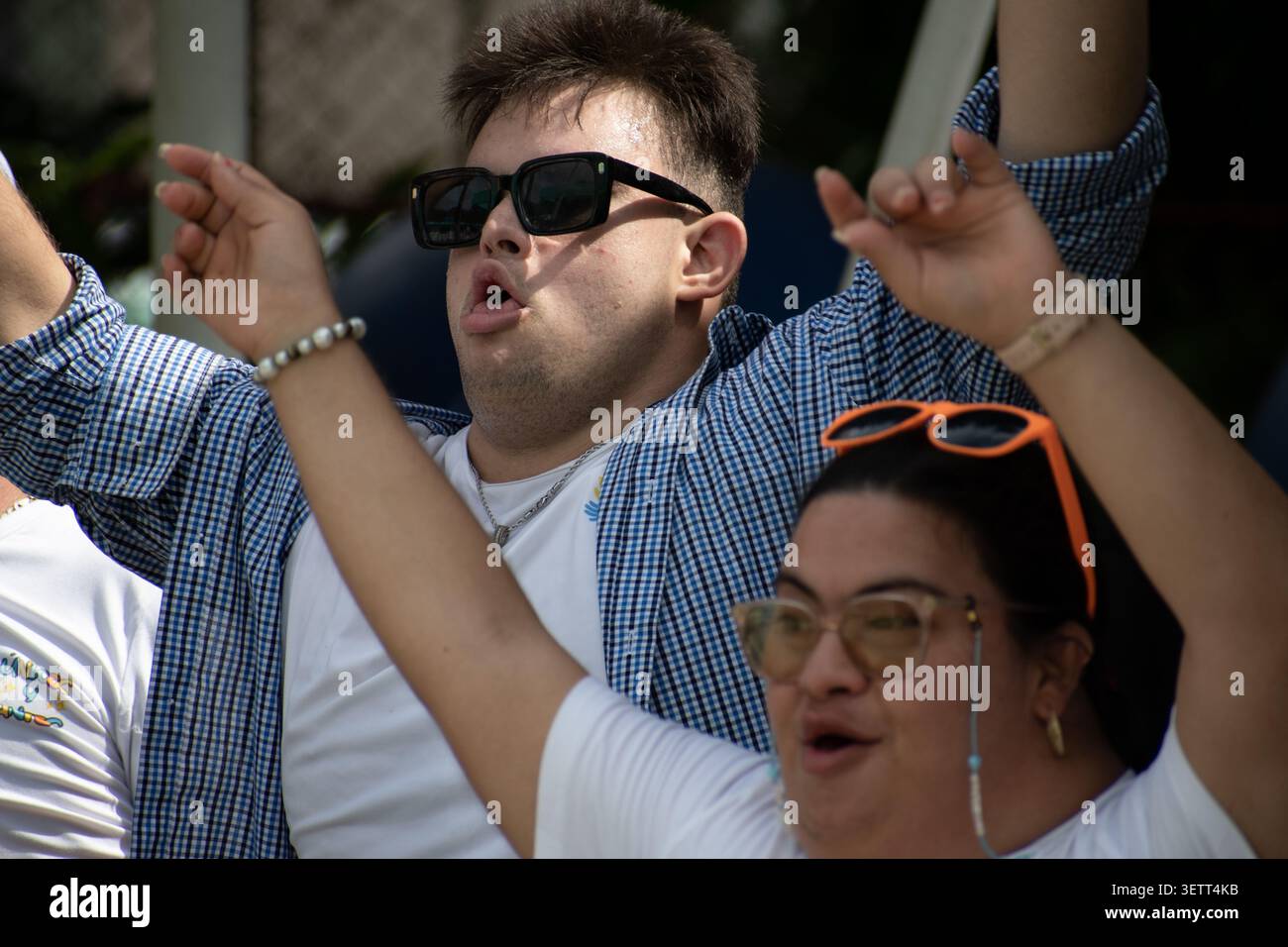 Giovane ed espressivo cubano con sindrome di Down che celebra con le braccia sollevate durante un'attività musicale per il social pr "Únicos y Brillantes" Foto Stock