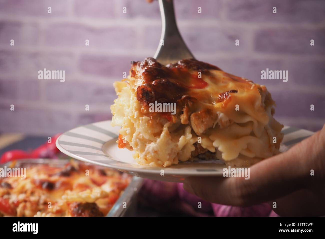 Servire una fetta di pasta al forno con il formaggio di un piatto Foto Stock