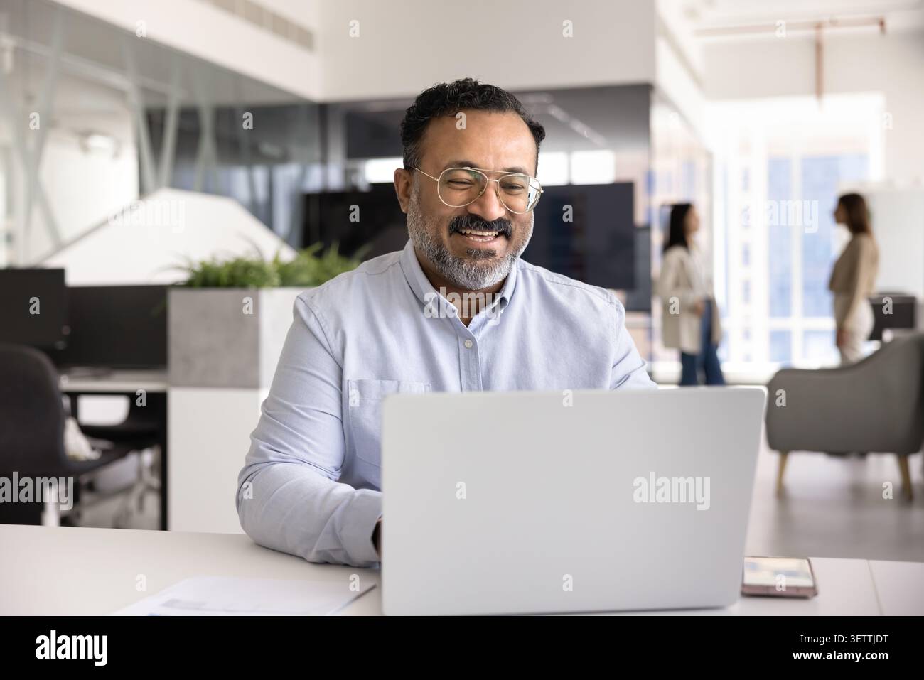Uomo d'affari che guarda contenuti online su un notebook e ride Foto Stock