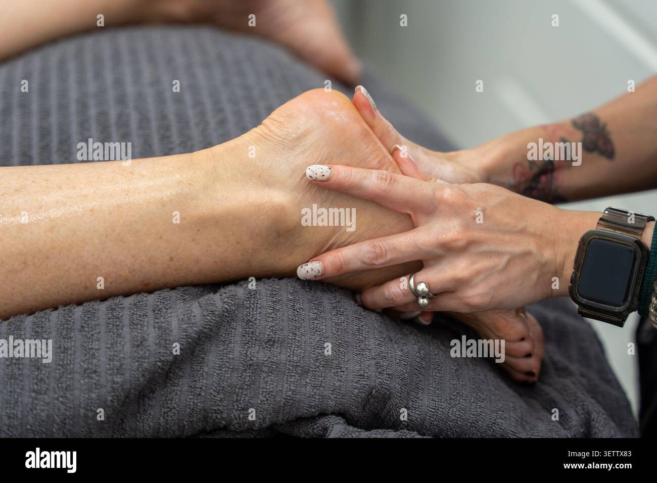 Persona che riceve un massaggio terapeutico professionale ai piedi su un asciugamano scuro Foto Stock