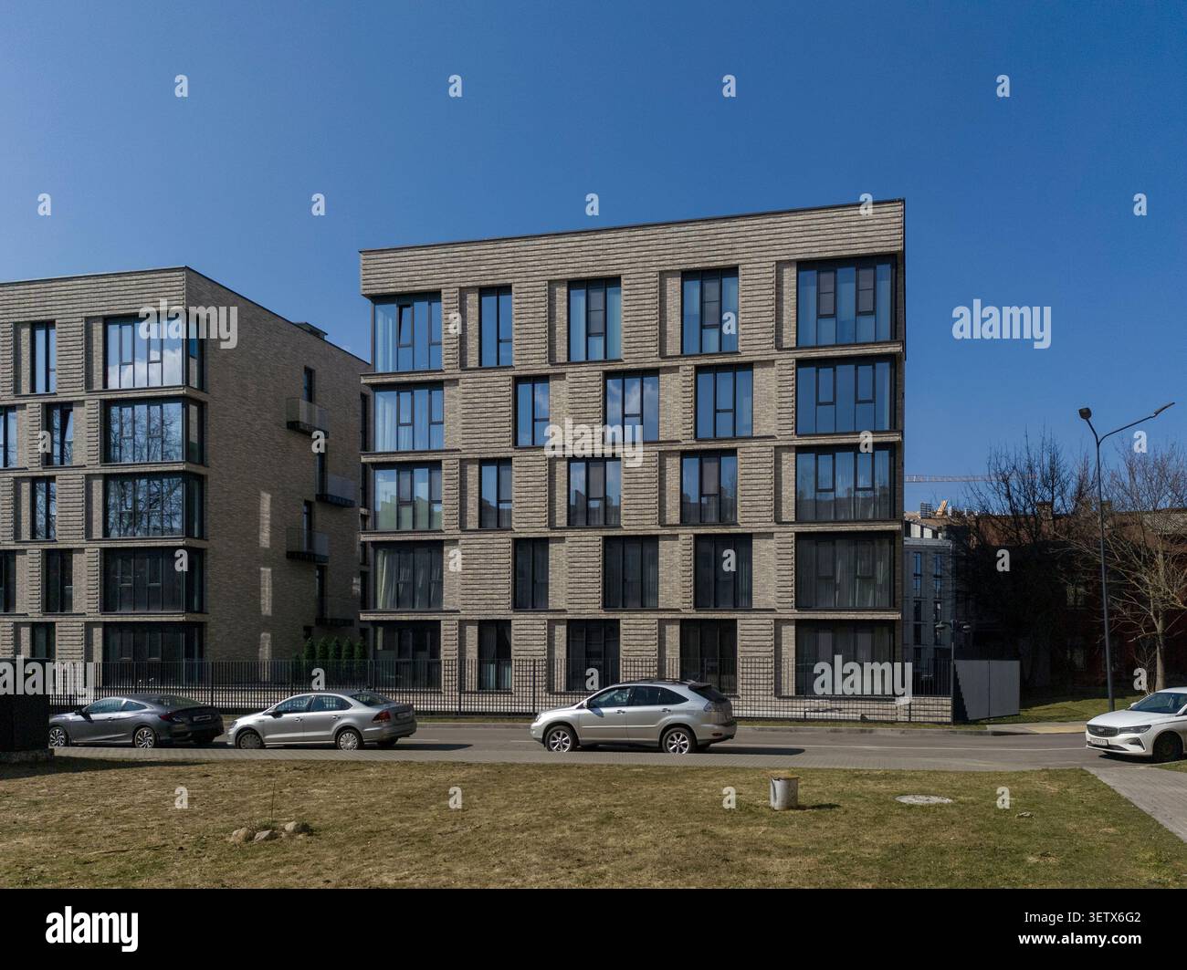 Moderno edificio di appartamenti con facciata geometrica e dintorni urbani. L'architettura residenziale presenta linee pulite e una composizione strutturata. Concetto Foto Stock