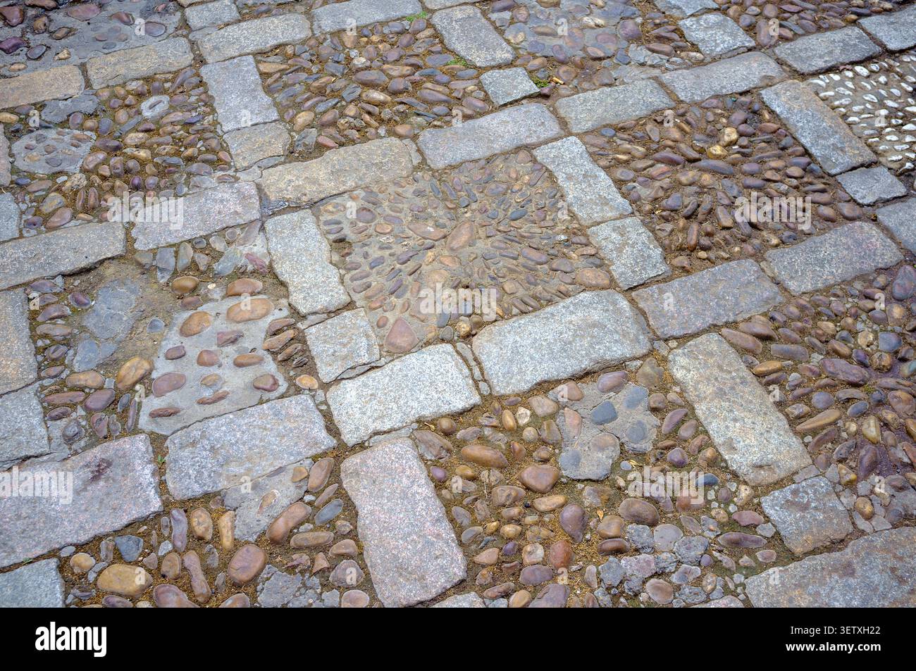 Un primo piano dei percorsi antichi a motivi mosaici di Siviglia, un misto di ciottoli e ghiaia fluviale. Le pietre precedenti sono state migliorate nel XX secolo. Foto Stock