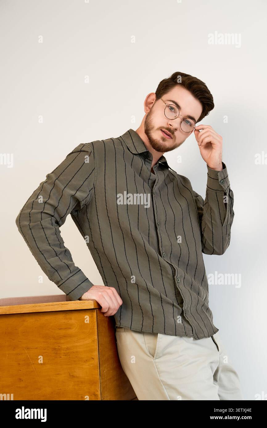 Questo giovane uomo sfoggia il suo elegante outfit casual in un moderno ambiente da studio Foto Stock