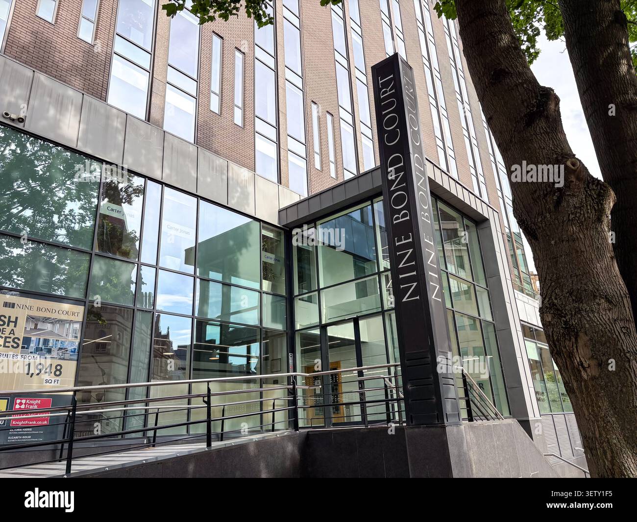 Moderno edificio di uffici in vetro e mattoni al Nine Bond Court, Leeds, Regno Unito, caratterizzato da insegne architettoniche contemporanee e grafica delle finestre. Foto Stock