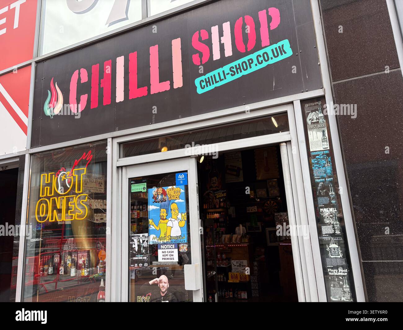 Negozio al dettaglio di fronte al Chilli Shop di Leeds, Regno Unito, specializzato in salsa calda e condimenti piccanti, con insegne al neon e poster sui prodotti. Foto Stock