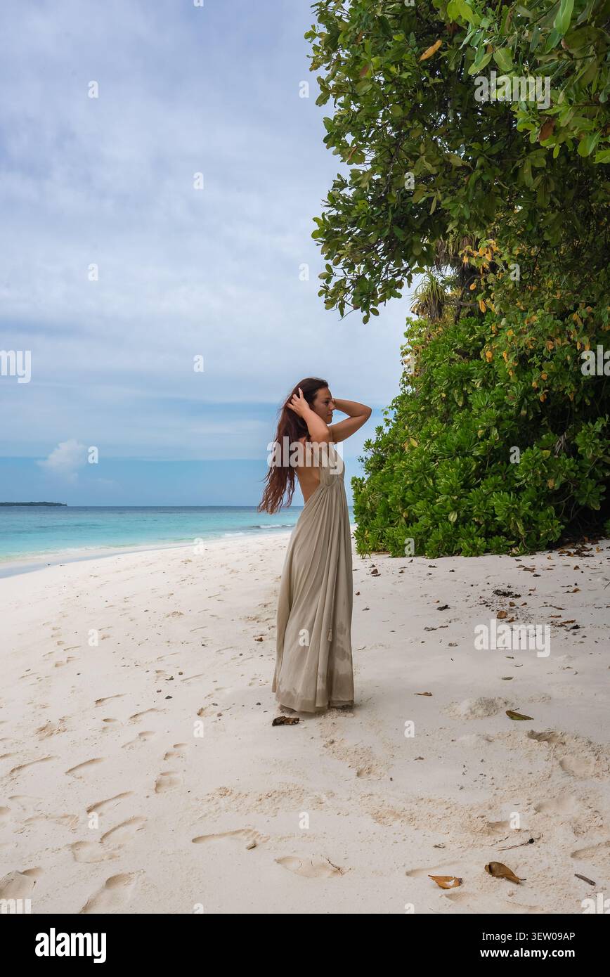 Donna sulla spiaggia di sabbia bianca con fondali bassi della laguna alle Maldive Foto Stock