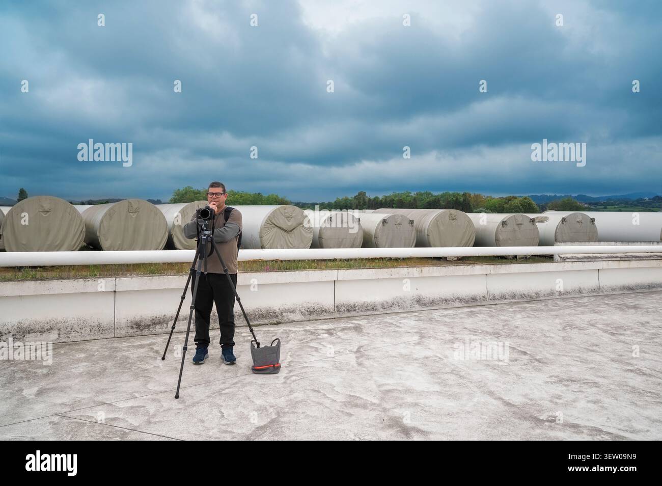 Uomo fotografo in piedi con la fotocamera su un cavalletto all'aperto Foto Stock
