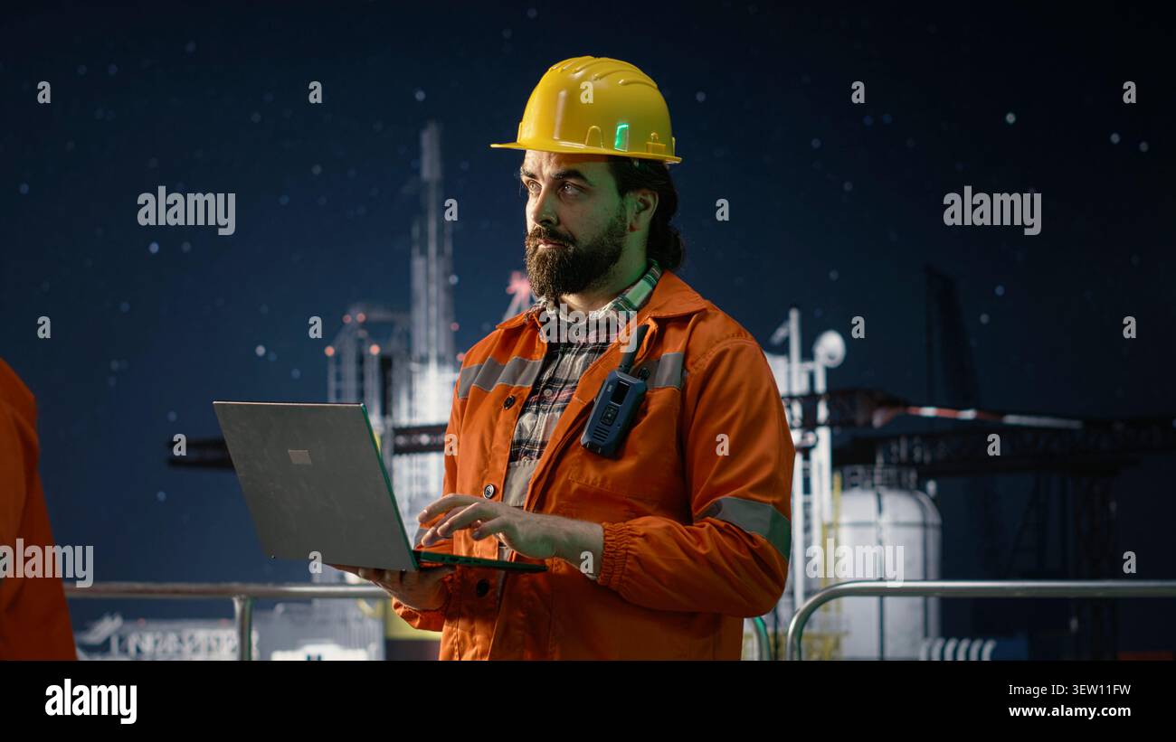 Gestore installazioni piattaforma offshore che gestisce i sistemi durante la crisi petrolifera utilizzando un laptop. Revisione professionale delle metriche di estrazione durante il blocco marittimo che influisce sulle operazioni Foto Stock
