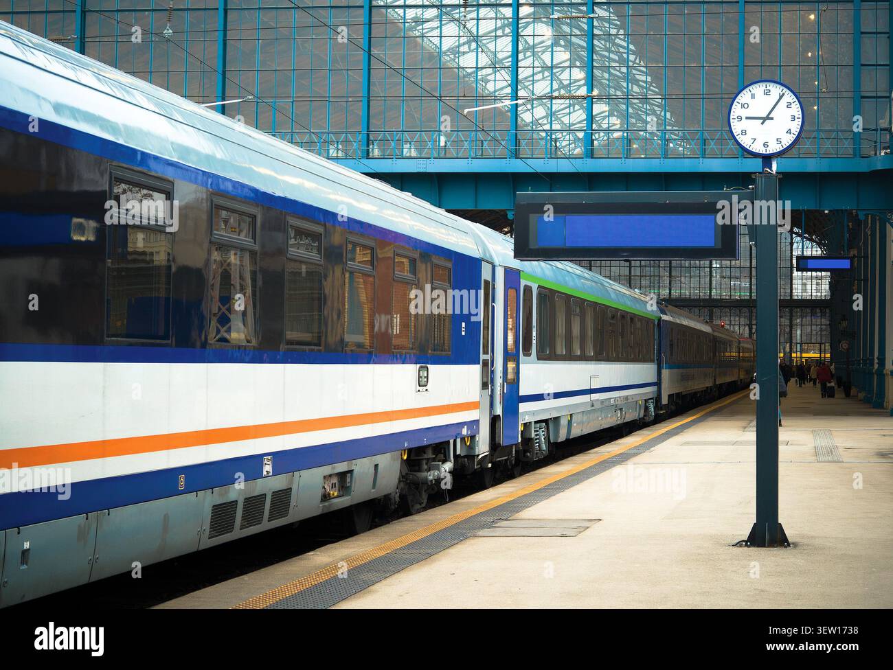 Il moderno treno passeggeri si fermò presso un binario all'interno della storica stazione ferroviaria Keleti di Budapest, Ungheria, con un orologio della stazione Foto Stock