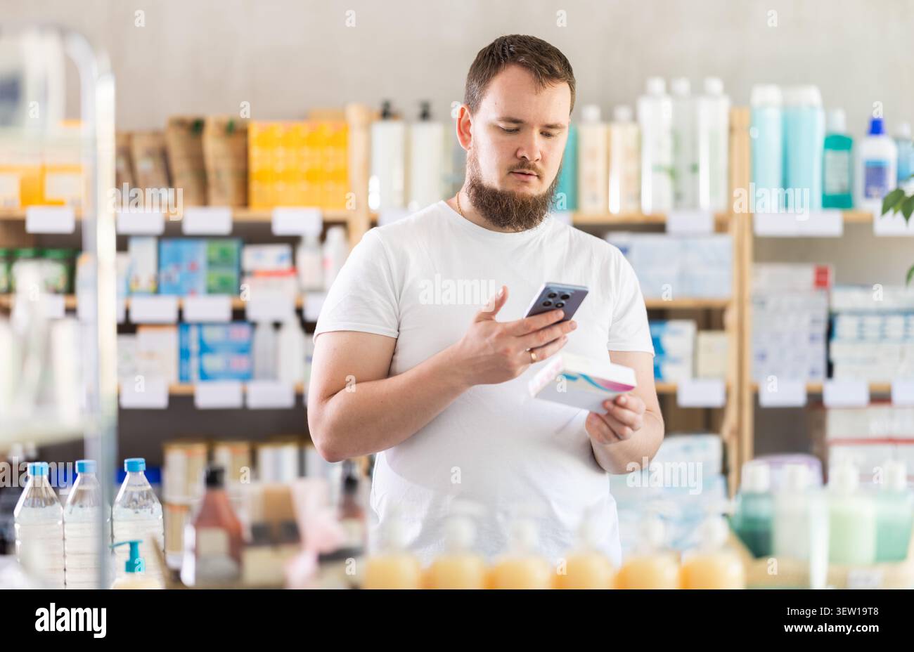 Man scansiona il codice sulla confezione di pillole per controllare la data di scadenza Foto Stock