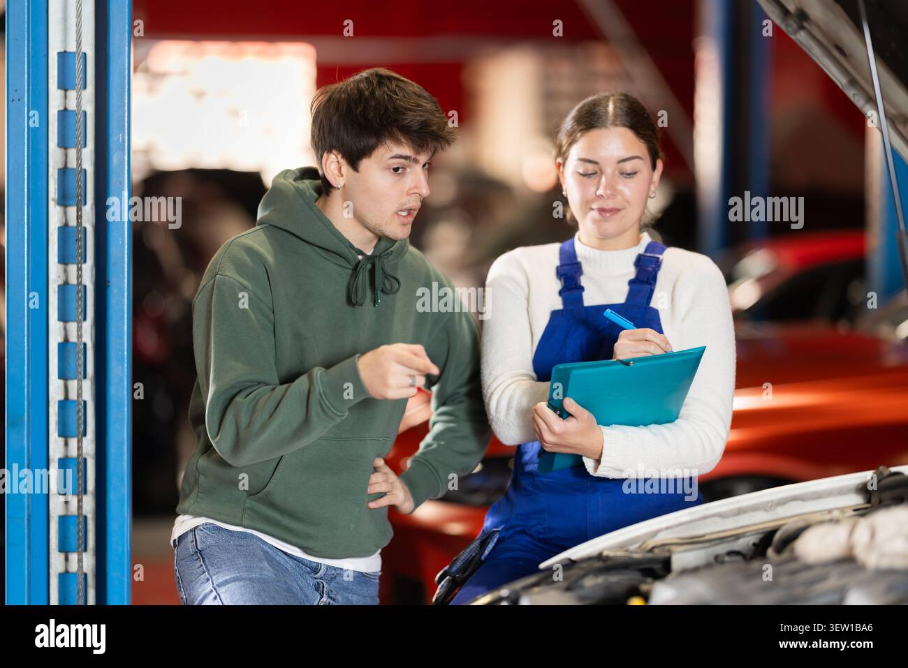un cliente maschio si consulta con un meccanico per riparare un'auto Foto Stock
