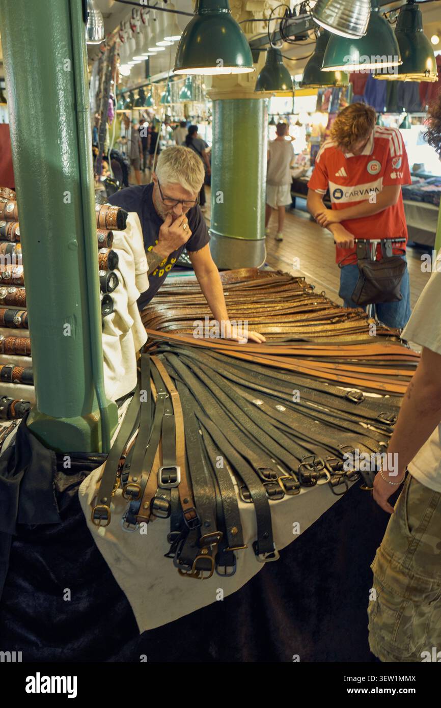 Il venditore organizza cinture in pelle al Pike Place Market di Seattle, mettendo in risalto l'artigianato locale e l'atmosfera vivace e iconica del mercato. Foto Stock