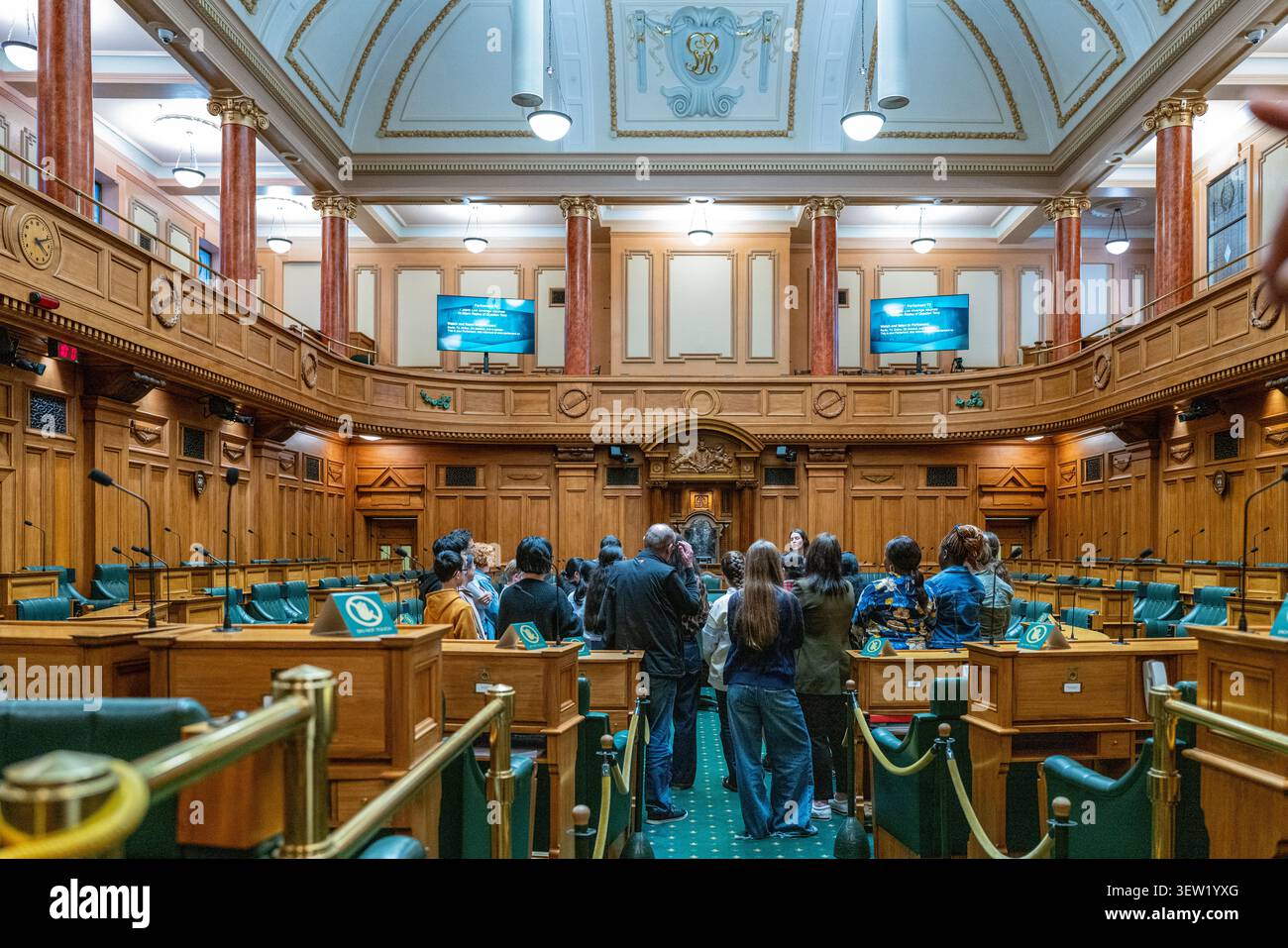 Un gruppo di tour si trova all'interno della camera di discussione del Parlamento della nuova Zelanda, illustrando l'impegno civico e l'accesso del pubblico alle istituzioni democratiche. Foto Stock
