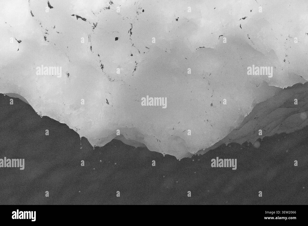 Foto in bianco e nero della neve che si scioglie e incontra l'acqua scura a Big Four Mountain, Washington, che mostra il contrasto tra la consistenza del ghiaccio e la superficie riflettente Foto Stock