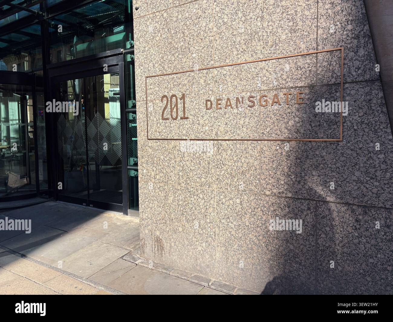 Ingresso moderno all'edificio per uffici con cartello al 201 di Deansgate, Manchester, Regno Unito. Facciata in granito lucido con porte girevoli in vetro. Foto Stock