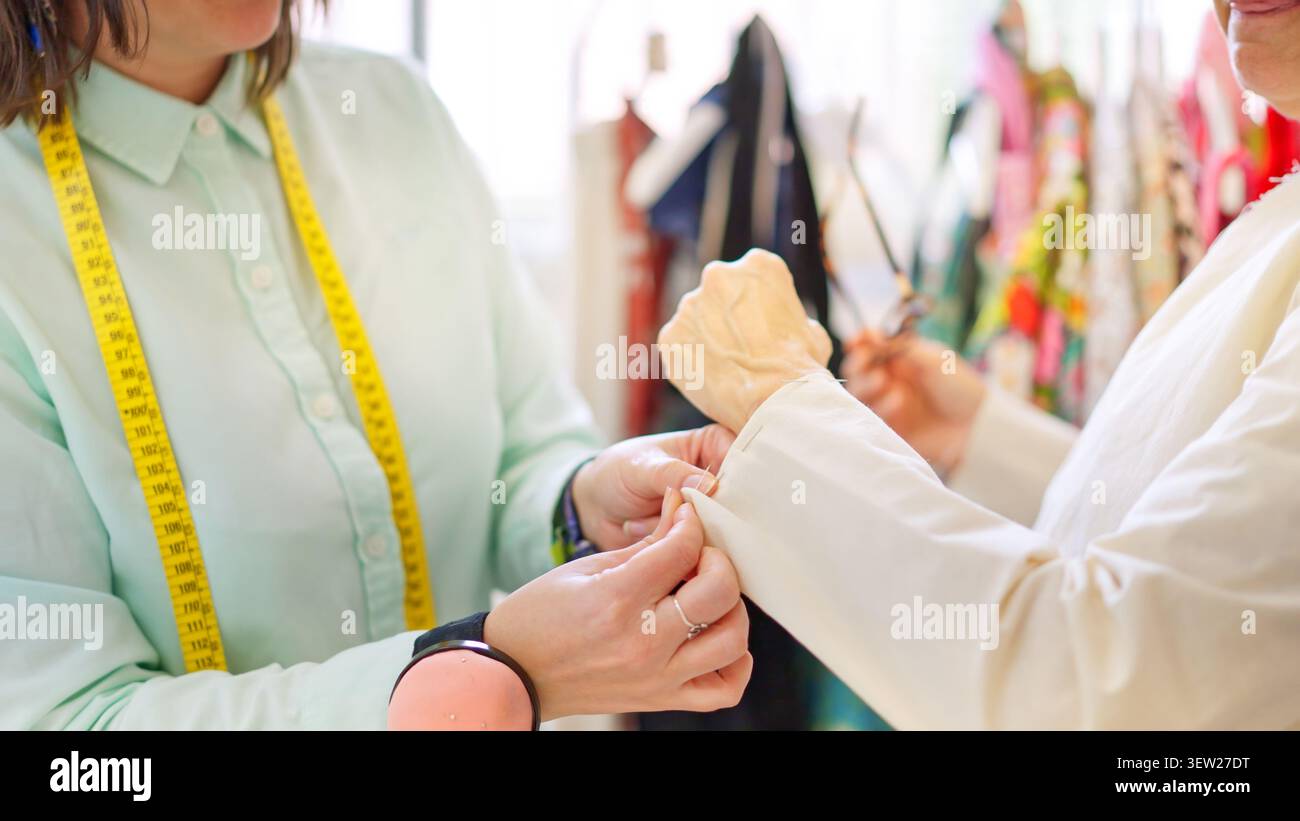 Sartoria che indossa indumenti per il cliente durante l'officina Foto Stock