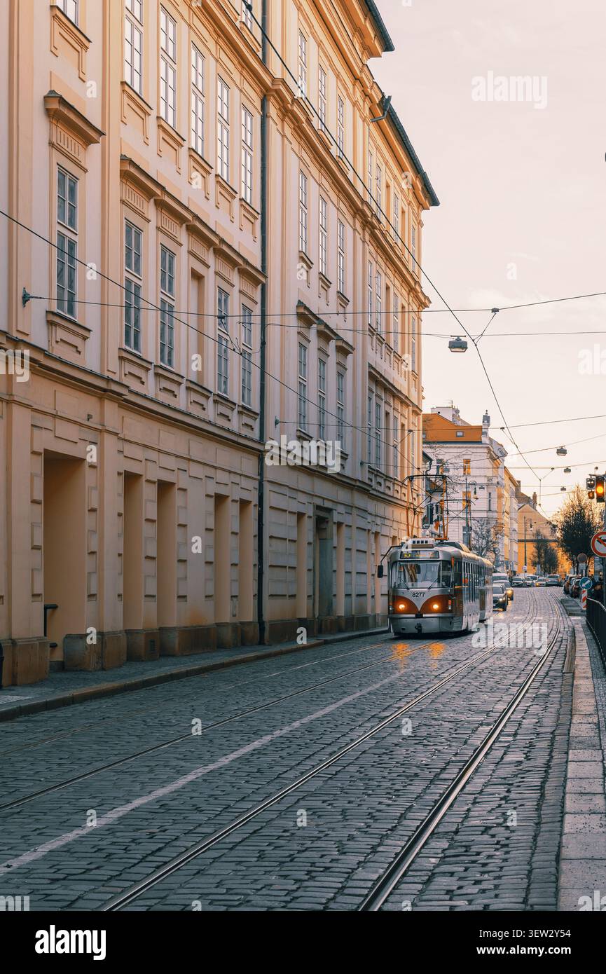 Vista frontale di un iconico tram storico T3 che procede lungo una strada acciottolata fiancheggiata da facciate architettoniche classiche al crepuscolo a Praga, Repubblica Ceca Foto Stock