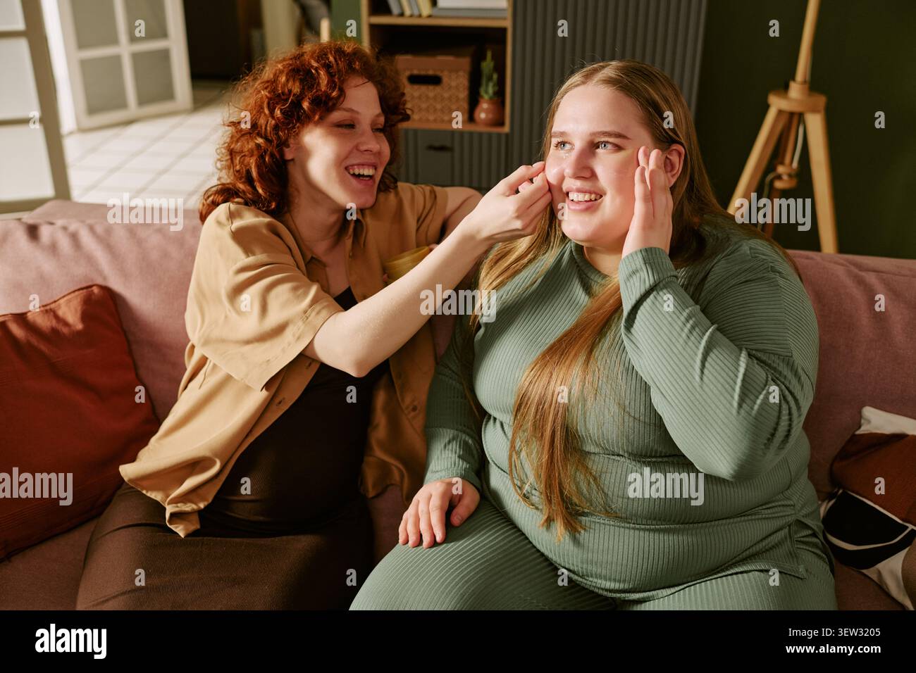 Plus size Women che applicano il trucco durante la sessione di bellezza Friendly Home Foto Stock
