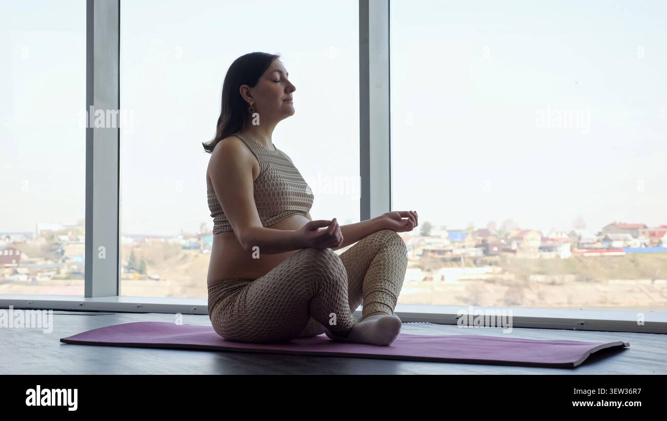 Donna incinta che medita in yoga posa per il benessere Foto Stock