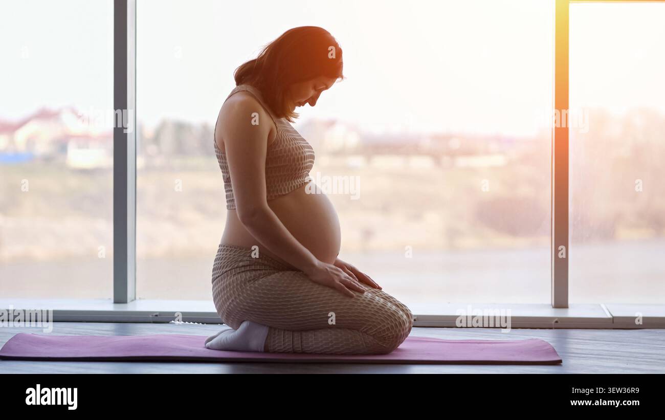 Donna incinta che pratica yoga per il benessere prenatale Foto Stock