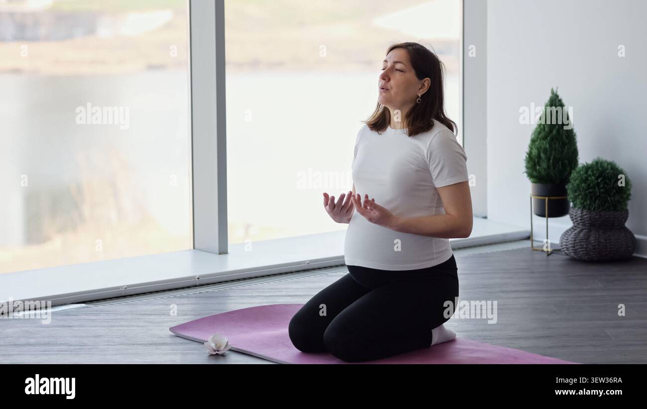 Donna incinta che meditava e praticava yoga prenatale a casa Foto Stock
