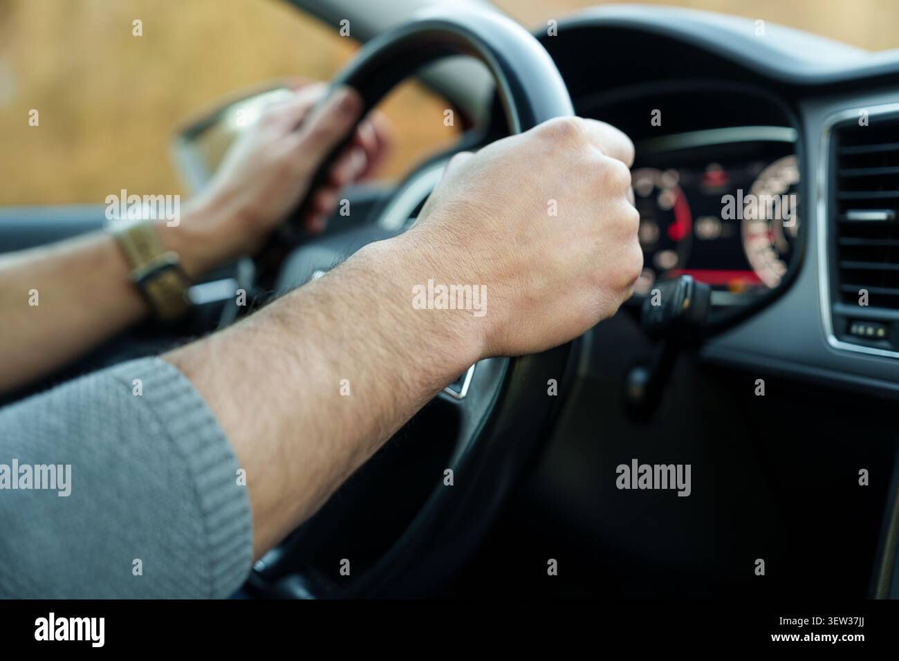 Mani maschili che tengono il volante durante la guida Foto Stock