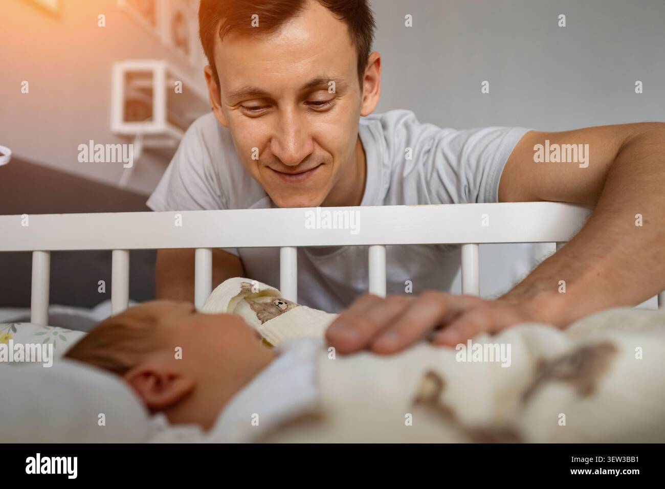Padre che guarda il bambino che dorme tranquillamente nella culla Foto Stock