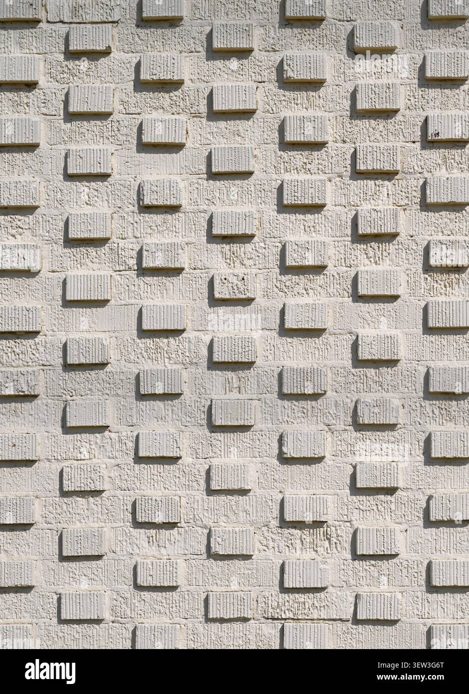 Primo piano verticale di una superficie muraria in mattoni 3D color crema verniciata con mattoni sporgenti in una griglia Foto Stock