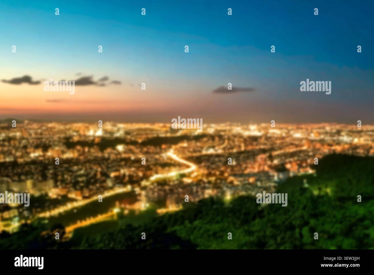 Le luci di una città notturna con orizzonte blu bokeh circolare. Cerchi di luce astratti colorati dalle lanterne stradali sfocati al crepuscolo serale. Foto Stock