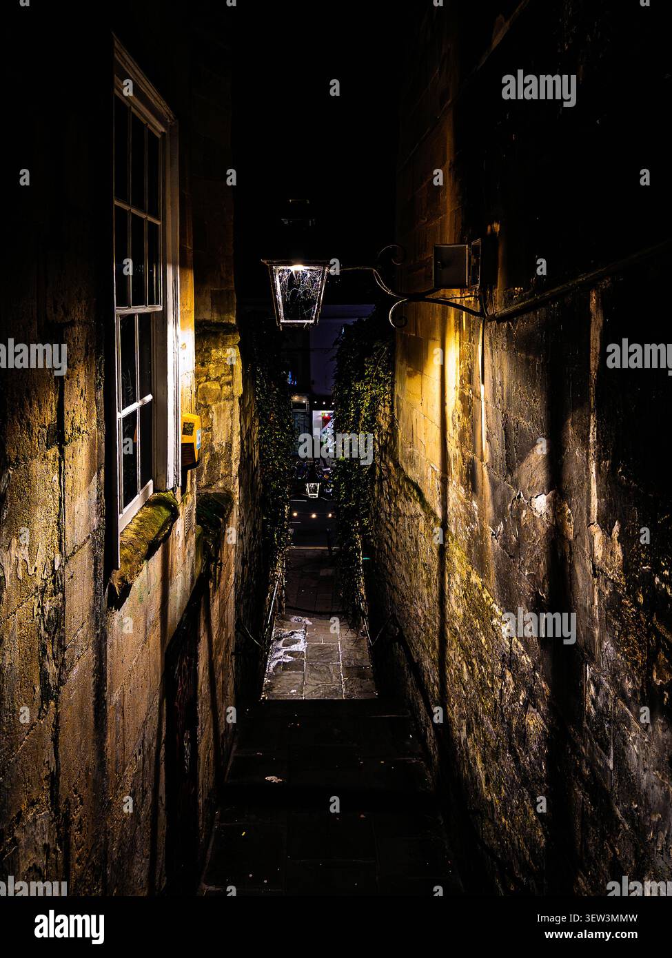 Un vicolo buio e suggestivo a Bath con forti ombre, luce lanterna e pareti in pietra intemprata, adatto per l'uso in copertina di libri Foto Stock