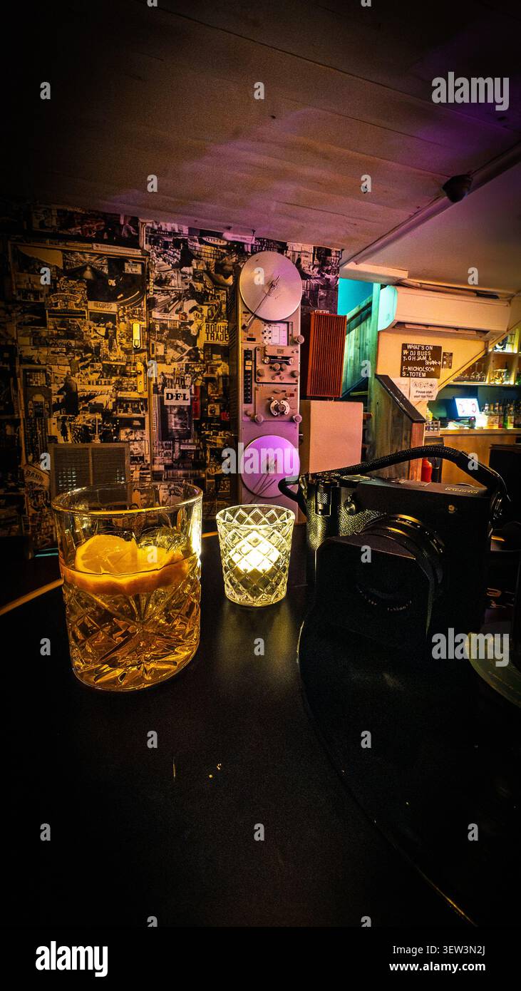 Interno di Dead Wax a Brighton con illuminazione soffusa, bevande sul tavolo e decorazioni a parete in stile collage - Immagine stock catturata con smartphone