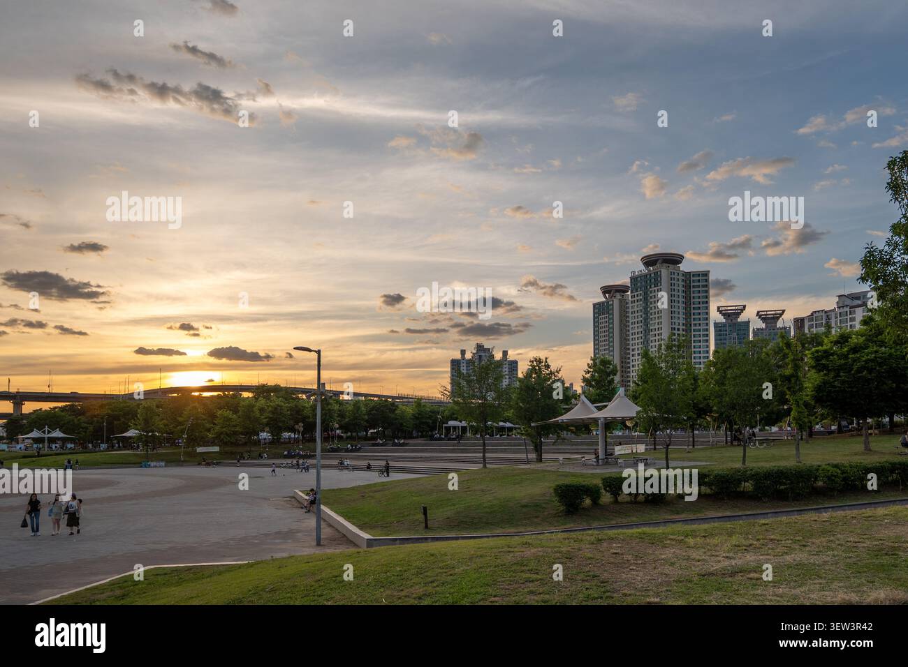 Un tramonto sereno dell'ora dorata sul fiume Han e sul ponte Cheongdam, con complessi residenziali che si ergono sopra il parco Ttukseom Hangang a Seoul Foto Stock