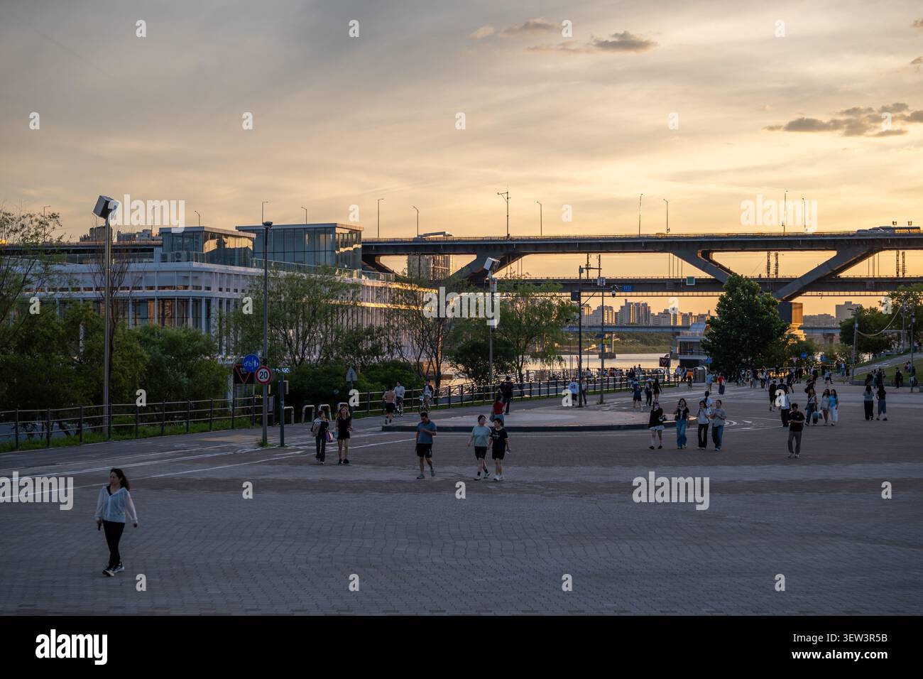 Una vista pacifica dell'ora dorata del fiume Han e del ponte Cheongdam, con i cittadini che si godono la loro passeggiata serale al parco Ttukseom Hangang a Seoul. Foto Stock