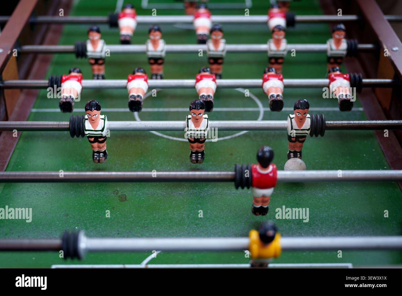 Primo piano di una classica partita di calcio balilla con giocatori in miniatura su un campo verde Foto Stock