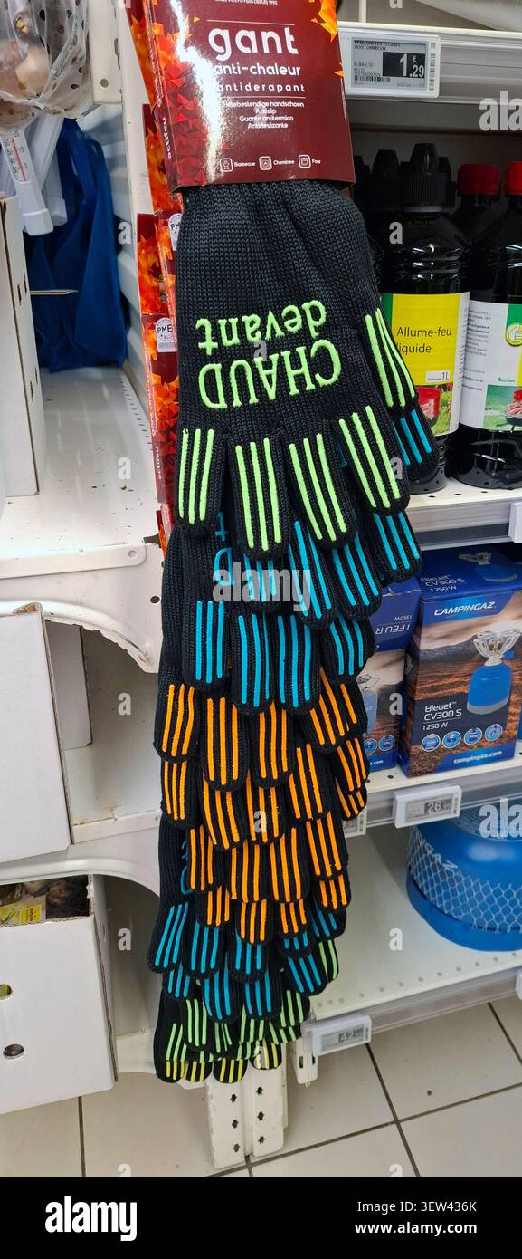 DARDILLY, FRANCIA - 3 novembre 2025. I guanti da cucina resistenti al calore sono in vendita in un supermercato francese. I guanti mostrano la frase Chaud devant i. Foto Stock