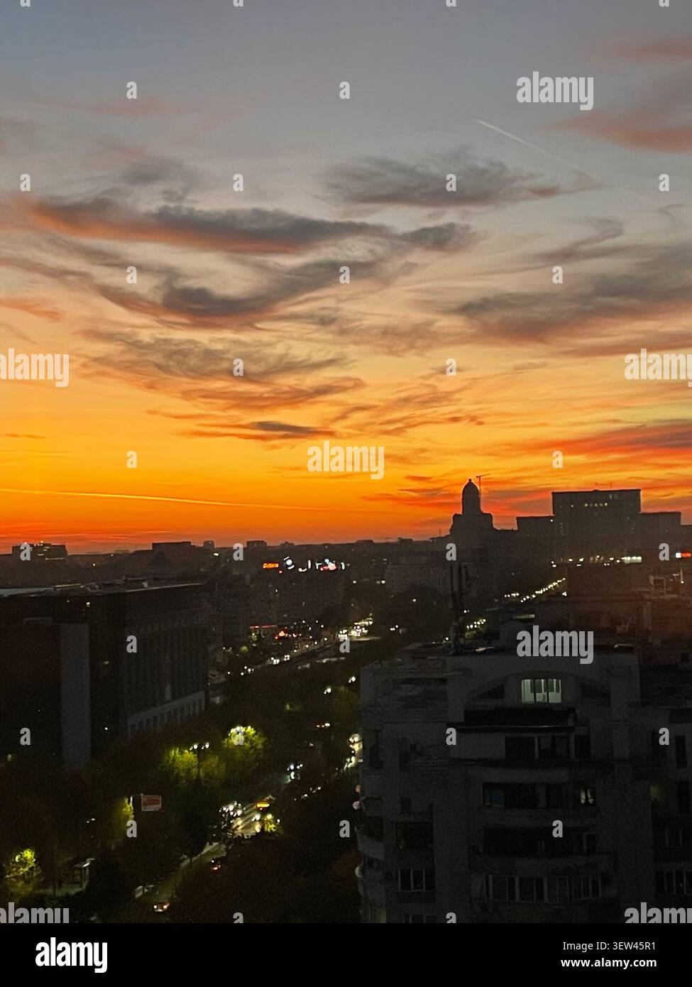 Tramonto mozzafiato sullo skyline di Bucarest, cielo arancione e viola che si riflette sull'architettura urbana della capitale rumena - Immagine stock catturata con smartphone