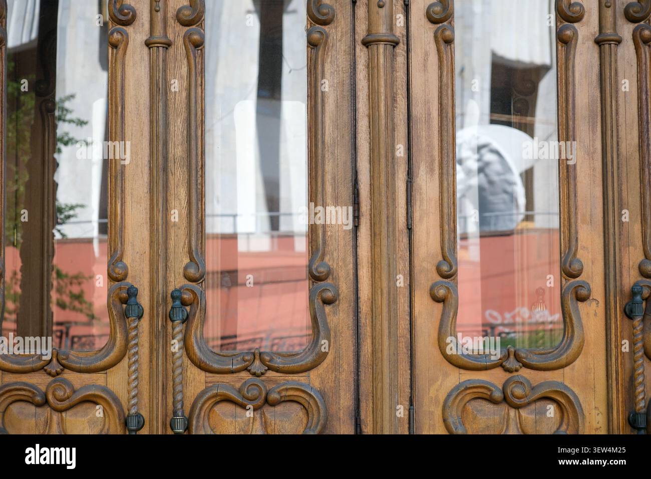 Le porte in legno splendidamente lavorate mostrano riflessi di vivaci attività nelle vicinanze. Foto Stock