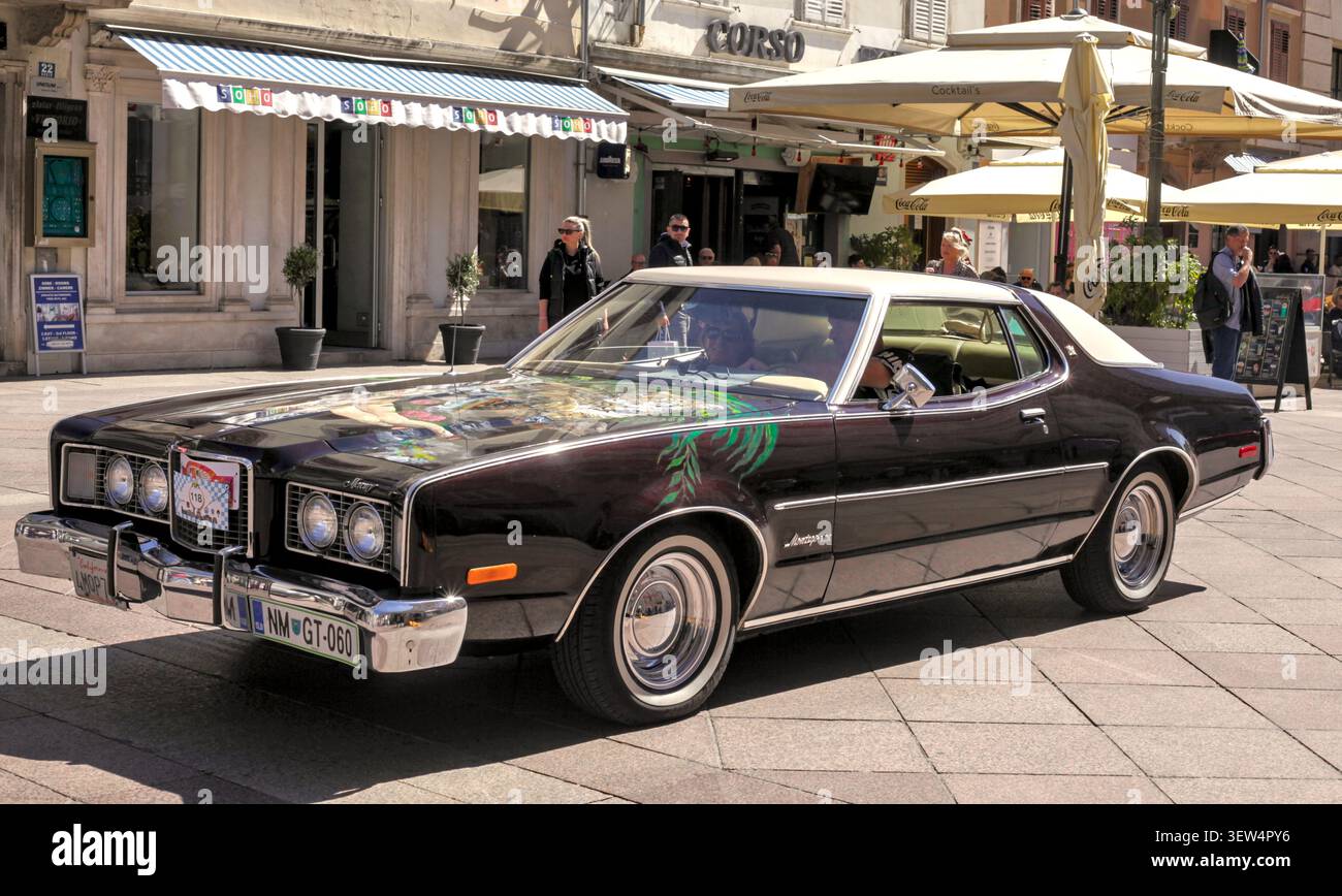 Classic Brown Mercury Montego MX Coupe con esclusiva arte del cappuccio passando davanti ai caffè all'aperto al Rally Oldtimer in via Korzo a Rijeka, Croazia. Foto Stock