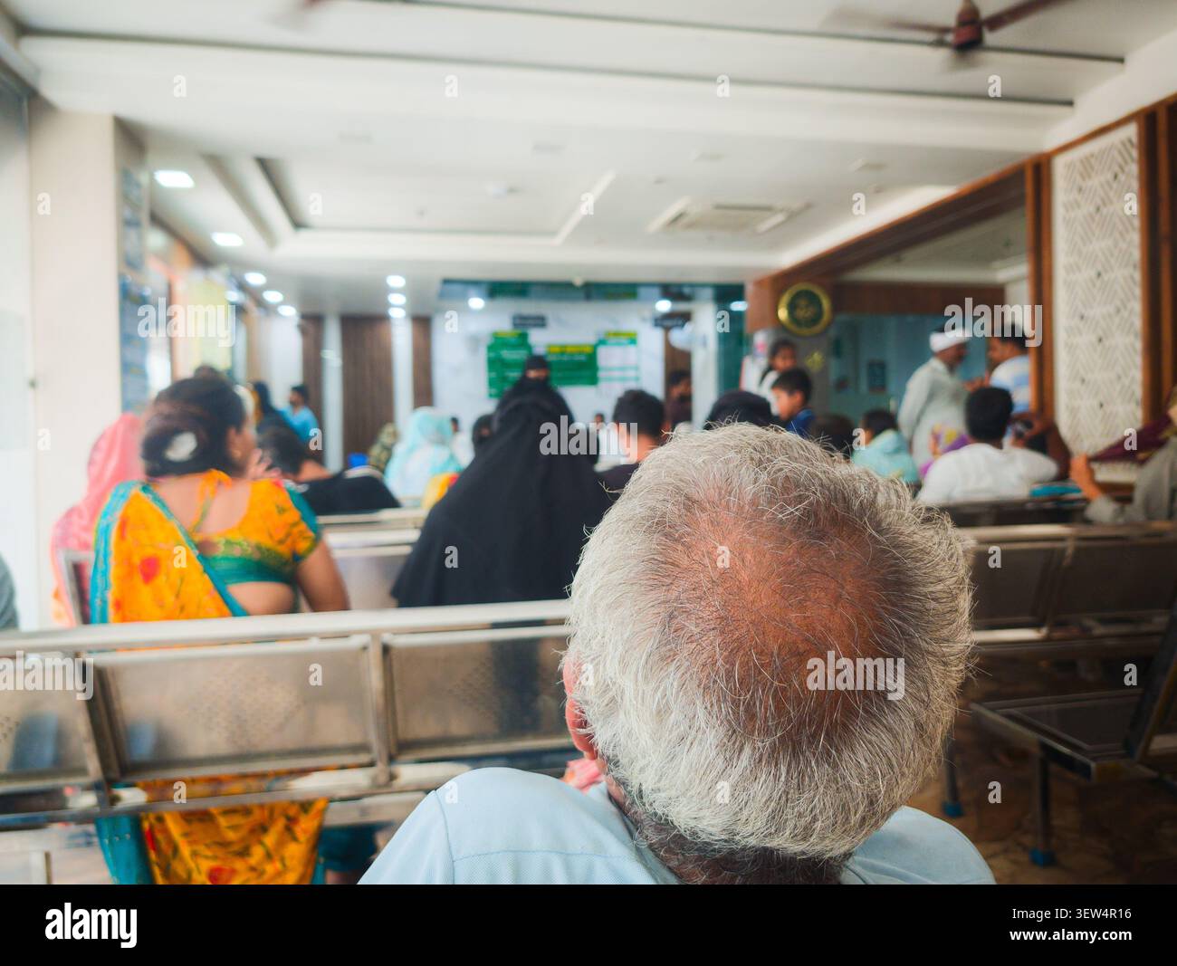 Pazienti e famiglie attendono nella lobby dell'ospedale di maternità in India, riflettendo l'assistenza sanitaria quotidiana, la speranza e il viaggio verso una nuova vita. - Immagine stock catturata con smartphone